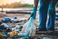 A close-up view of a volunteer man collecting plastic bottles during a clean-up day on the sea beach