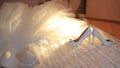 Close-up view of the wedding rings between bride highheel lying near the dress on the bed. The moving sunlight.