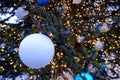 Close up view on wet misted matte white christmas ball with water drops on christmas tree branch with lights