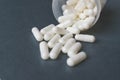 Close up view of white capsules spilling on gray background with space