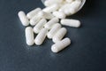 Close up view of white capsules spilling on gray background with space
