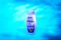 Close-up view of the white hand and body lotion bottle product with Marina Natural trademark and purple label on blue background