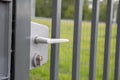 A close-up view of the white handle on the steel fence gate.