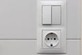 Close up view of white light swithch and socket pair on white tile. Building construction elements concept. Interior. Royalty Free Stock Photo