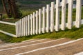 A close-up view of a white wooden fence stretching across the lawn near a concrete staircase Royalty Free Stock Photo