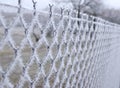 Close-up view of a wire fence with frost with ice crystals under a blue sky with a blurred background Royalty Free Stock Photo