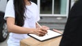 Close up view woman customer signing on digital tablet and receiving package from delivery man. Royalty Free Stock Photo