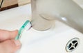 Close up view of woman hand cleaning bathroom sink with toothbrush. Home cleaning hack. Royalty Free Stock Photo