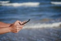 Close up view of woman hands holding mobile phone at the beach. Summer and technology concept Royalty Free Stock Photo