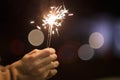 Close up view of woman hands holding sparkler, celebrating new year eve