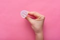 Close up view of woman holding menstrual cup over rose background, woman`s period, menstrual cup in hands, modern method