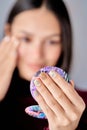 Close-up view of a woman holding a portable make-up mirror with her manicure nails. Royalty Free Stock Photo