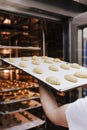 Close up view of woman holding holding rack of croissants in a bakery