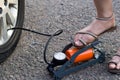 Close-up view of woman inflating car tyre by mechanical foot air pump Royalty Free Stock Photo