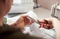 Working female hands using scissors for cutting off textile in stitching process. Close up view. Blurred background.