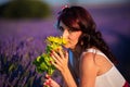 Close up view of woman looking at camera while smelling flowers outdoors in a lavender field Royalty Free Stock Photo