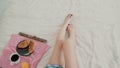 Close-up view of woman s foot. Young girl lying on the bed, having breakfast in living room.