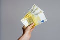 Close up view of a woman`s hand holding a pile of euro banknotes   money on a gray background . The economic impact of coronaviru Royalty Free Stock Photo