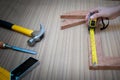 Close up view of a woman is hands measuring wooden plank with a Tape measure with a set collection of working hand tools Royalty Free Stock Photo