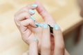Close-up view of a woman`s hands painting her nails with blue-green nail polish. Concept of body care and beauty