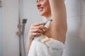 Close-up view of woman shaving her armpits with razor in shower cabin. Depilatory procedure at bathroom