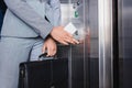 Close-up view of woman in suit holding electronic key and pushing button