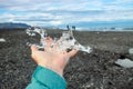 Close up view of woman tourist holding glacier ice on hand.