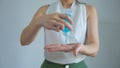 Close up view of woman in white dress using small portable antibacterial hand sanitizer on hands