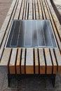 Close-up view of wooden bench with integrated solar panel for charging gadgets on the street. Concept of smart city in Kyiv Royalty Free Stock Photo
