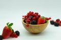 Close up view of a wooden bowl with strawberries, raspberries, blueberries, red currants and blackberries on a white background. Royalty Free Stock Photo