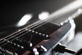 Close-up view of a wooden electric guitar fretboard with black frets, glossy finish, visible grain pattern, multiple strings