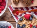 Close up view of wooden spoon between porridge with blueberries and raspberries and grain bread on wooden background. Royalty Free Stock Photo