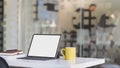 Close up view of workplace with blank screen tablet, office supplies  and coffee cup on white table with blurred  office room Royalty Free Stock Photo