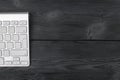 Close up view of a workplace with wireless computer keyboard, keys on old black wooden table background.