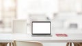 Close up view of workspace with open blank screen laptop, frame and notebook on white table with blurred office room Royalty Free Stock Photo