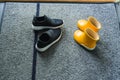 Close up view of yellow and black  pair summer kid shoes on mat near entrance door. Royalty Free Stock Photo