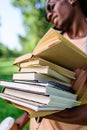 Young african american man holding pile of books in park Royalty Free Stock Photo