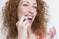 Close up view of a young beautiful woman eating blueberries over white background and smiling. Indoors and lifestyle. Healthy Royalty Free Stock Photo