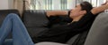 Close up view of female lying relaxed on black sofa in living room and talking on the phone Royalty Free Stock Photo