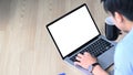 Young man drinking coffee and using computer laptop while lying on wooden floor. Royalty Free Stock Photo