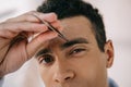 View of young man plucking eyebrows with tweezer Royalty Free Stock Photo