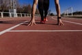 Close up view of young muscular athlete is at the start of the race tracks line at the stadium. Sports concept