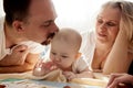 Close-up view of young parents, mom and dad, reading a children's book to their baby. Family training and education Royalty Free Stock Photo