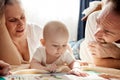 Close-up view of young parents, mom and dad, reading a children's book to their baby. Family training and education Royalty Free Stock Photo