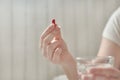 Close-up view of young woman`s hands. Girl in bed holding tablets or pills and glass of water. Blurred background Royalty Free Stock Photo