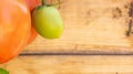 Close up of vine red Roma tomato and unripe green tomato on a wood background, useful for copy space or a web banner, depicting Royalty Free Stock Photo