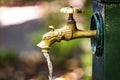 Close up of vintage brass tap with drinking water on the city street or park. Flowing water. Selective focus