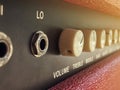 Close-up vintage cream volume knob of the boutique clean guitar amplifier with blurred brown control panel and red leather cover. Royalty Free Stock Photo