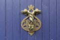 Close-up. Vintage handle for knocking on a blue wooden door in the form of two wriggling snakes