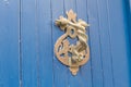 Close-up. Vintage handle for knocking on a blue wooden door in the form of two wriggling snakes